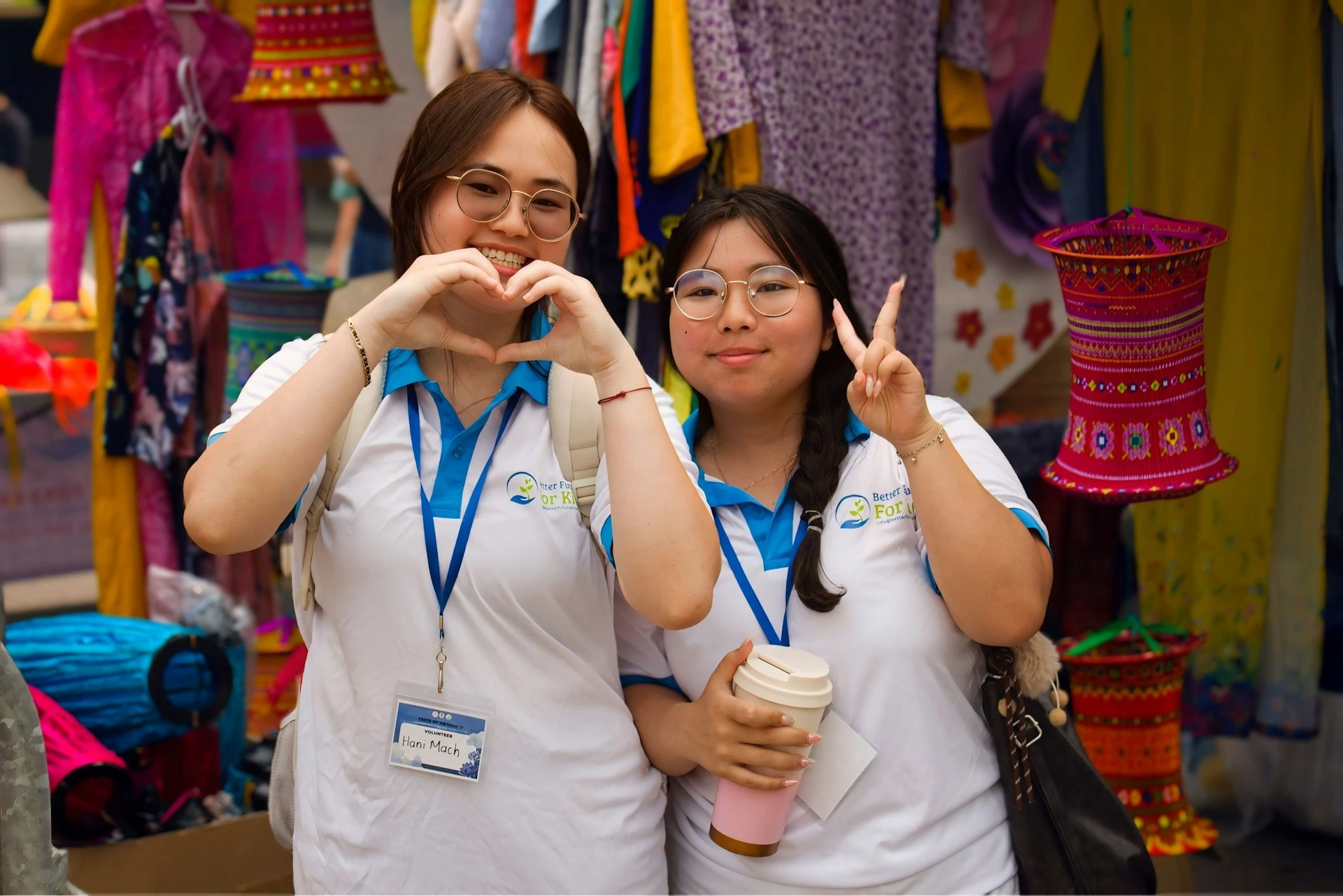 Two young women posing happily in a colorful market